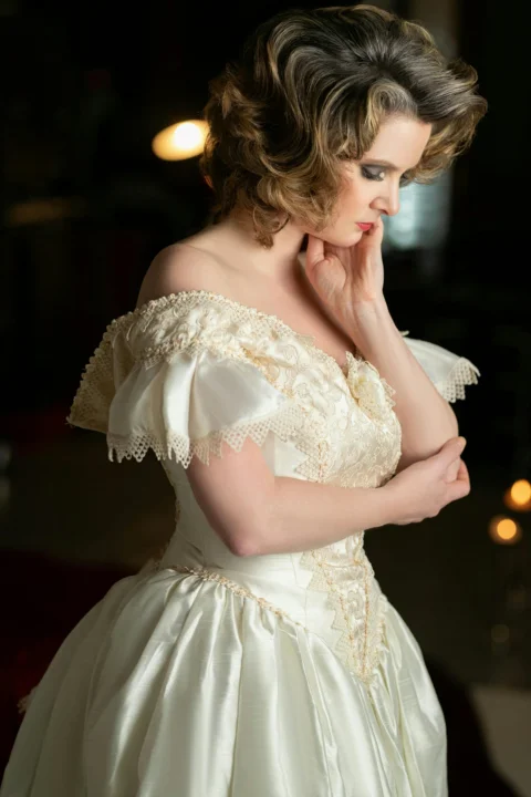 Woman in vintage dress poses thoughtfully