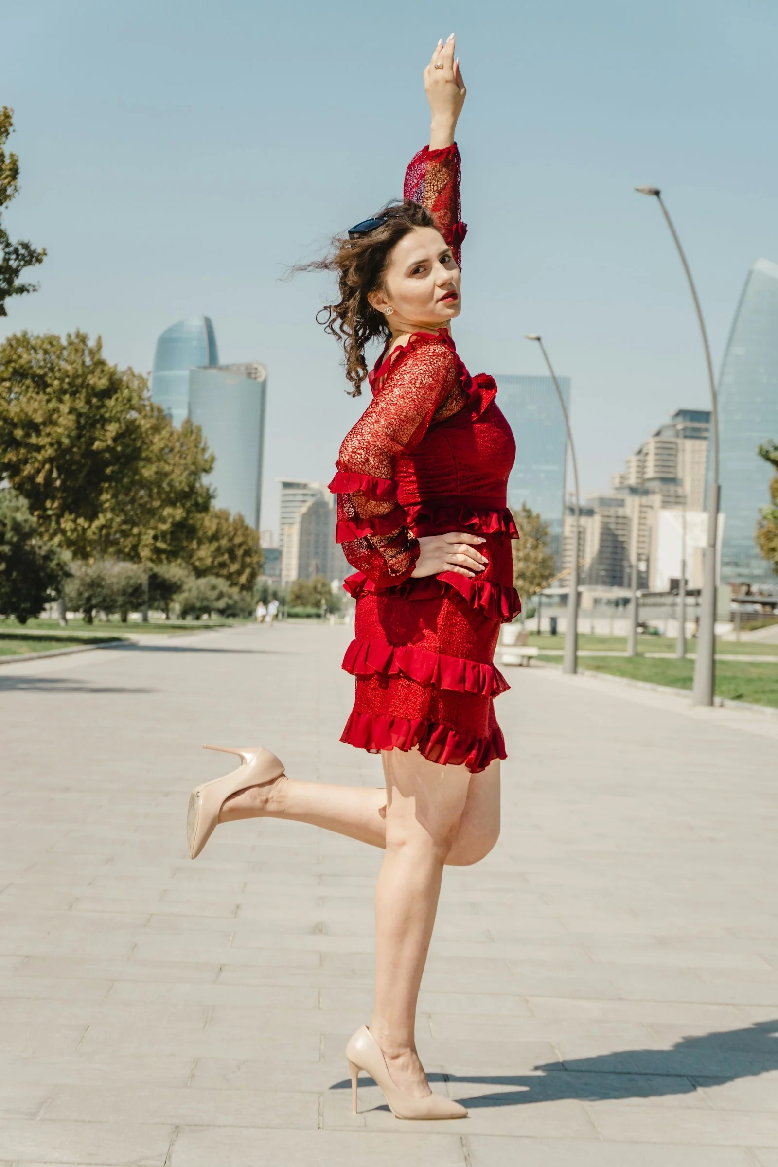 Stylish woman in red dress posing outdoors with city