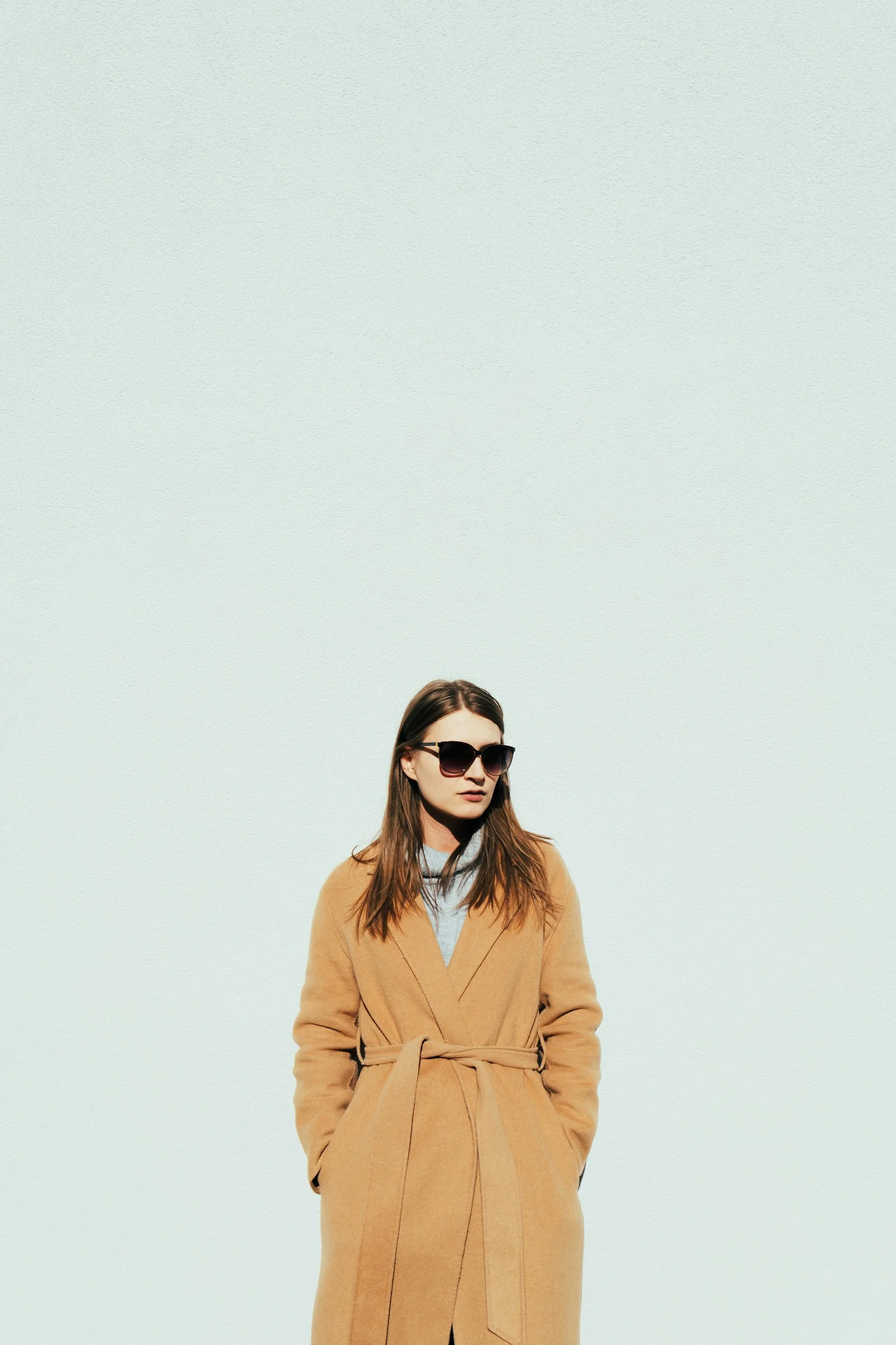 a woman in a tan coat and sunglasses