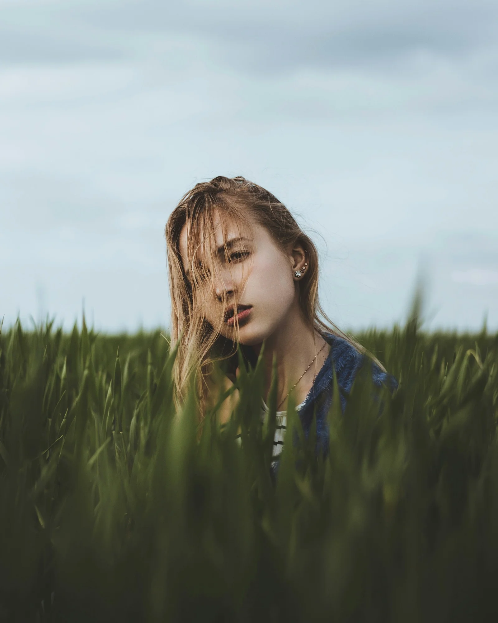 girl in blue jacket standing on green grass field during daytime