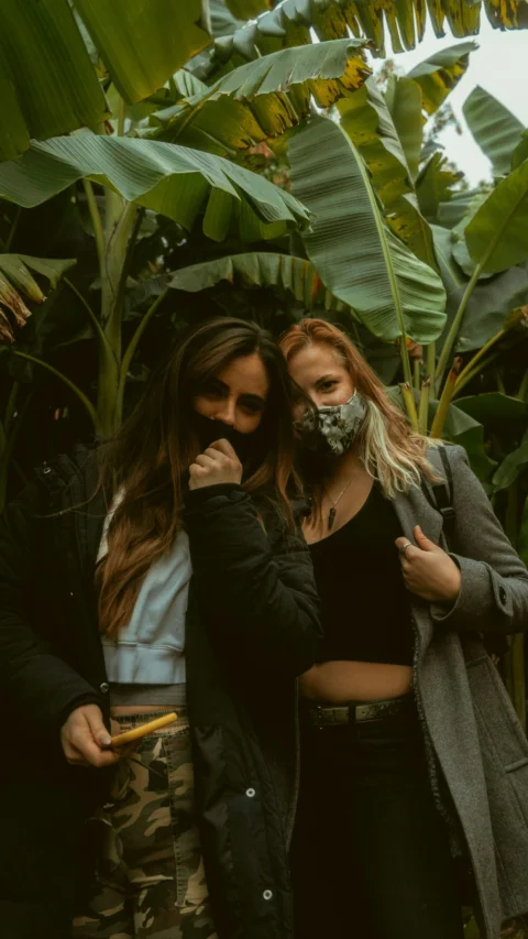 2 women smiling near green plant