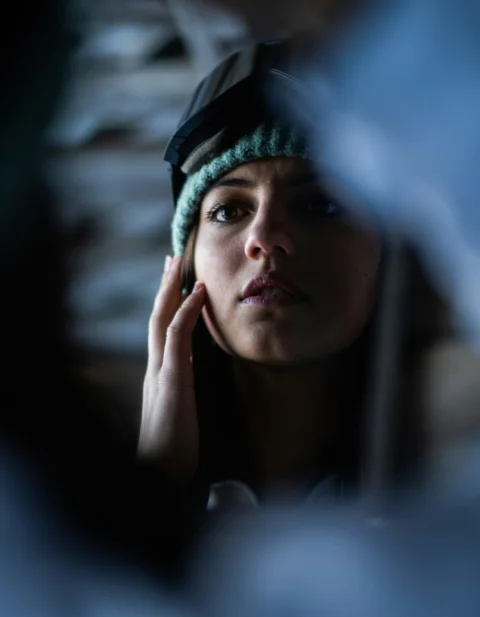 a woman wearing a hat and holding her hand to her ear