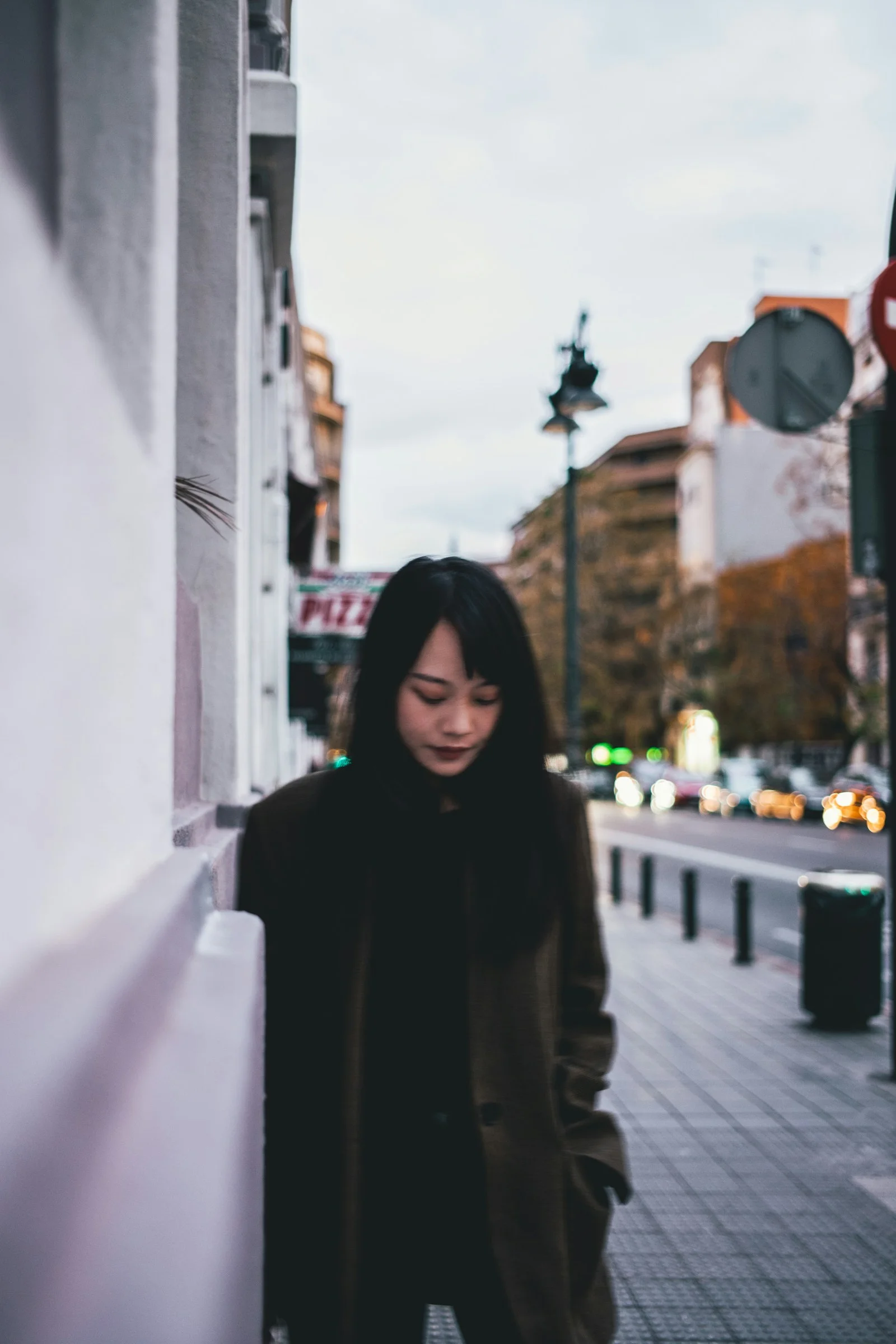 woman on sidewalk beside building near road