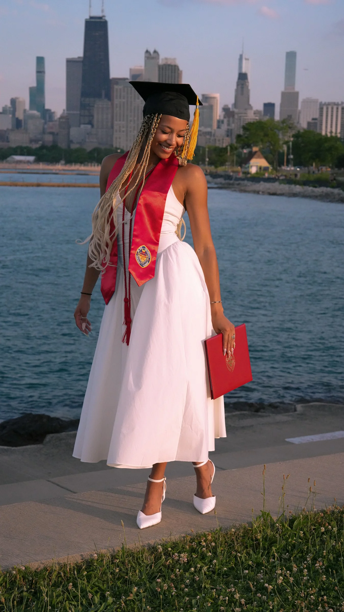 A woman in a graduation gown standing on a sidewalk