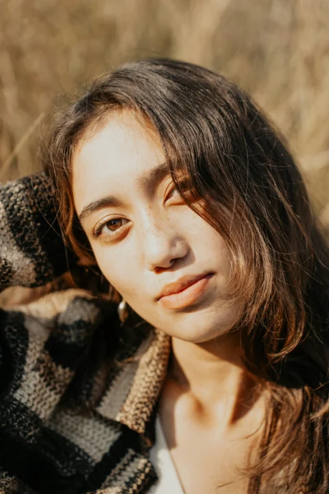 A woman is posing for a picture in a field
