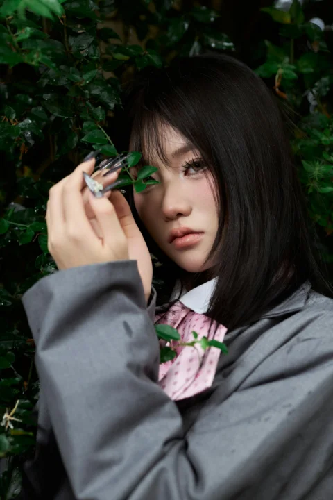 Young woman holding green leaves against a lush background
