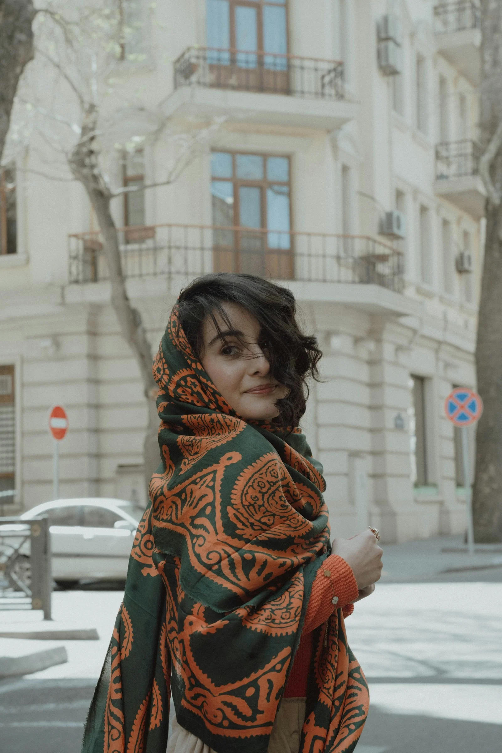 a woman is standing on the street wearing a scarf