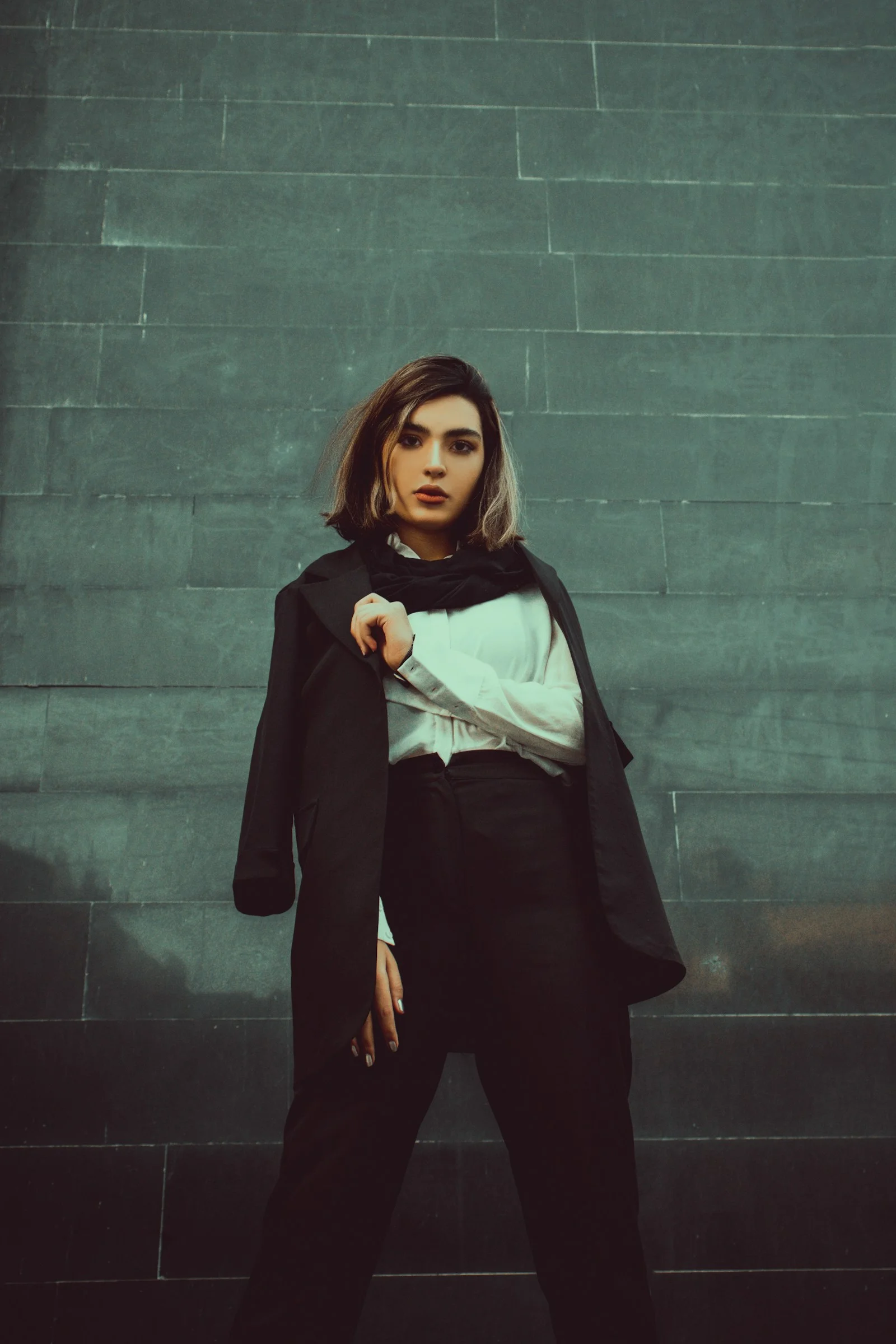 woman in black long sleeve dress standing beside gray wall