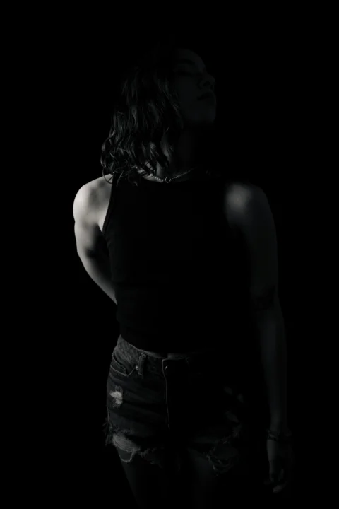 A woman poses in silhouette against blackness