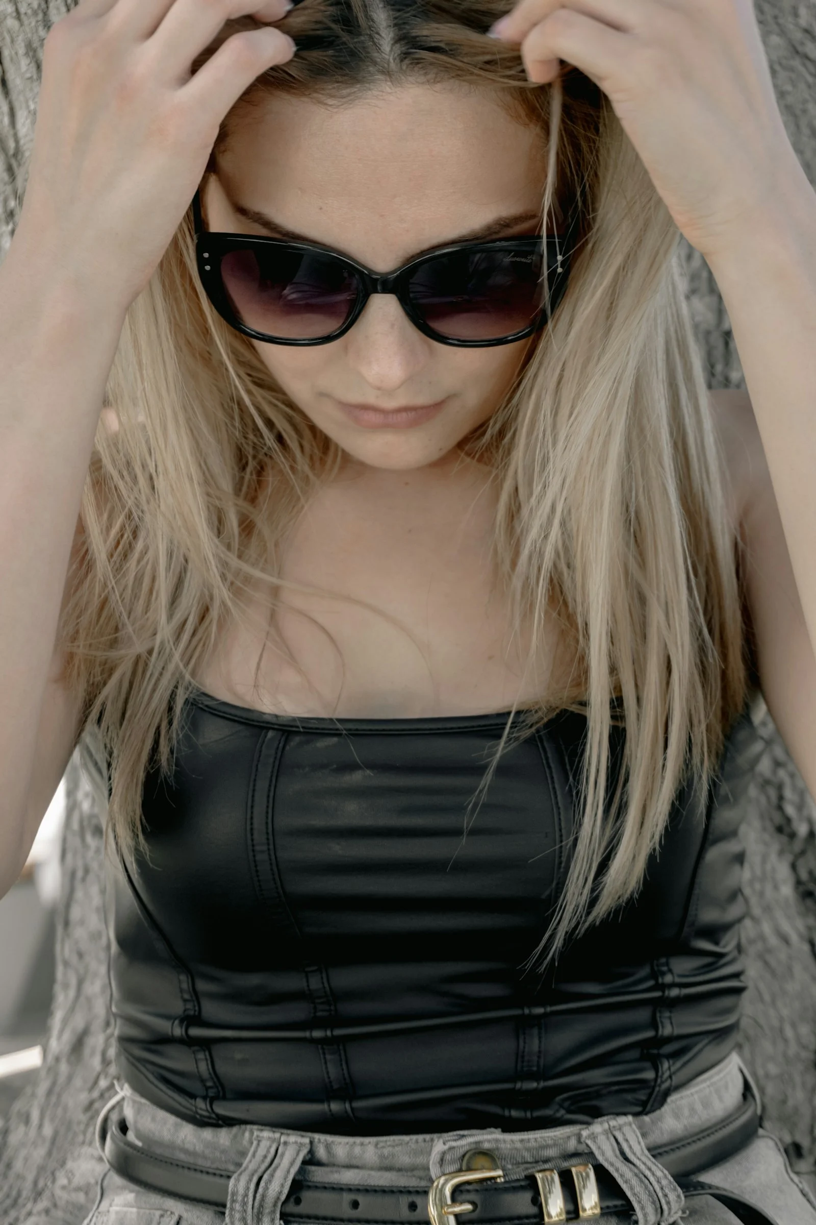 Blonde woman wearing sunglasses with hands in her hair