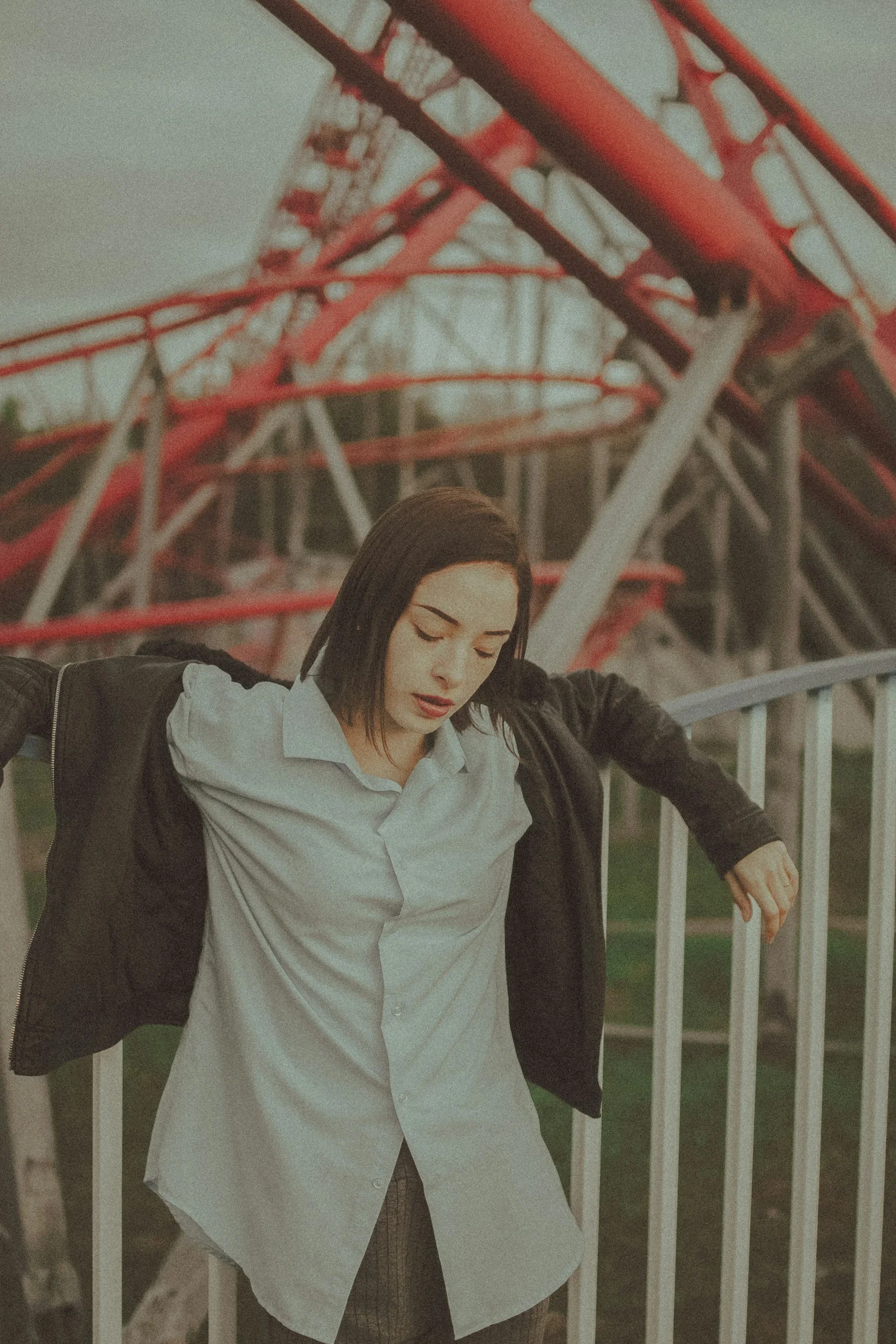 穿灰色长袖衬衫和黑色裤子的女性站在白色金属栅栏旁
