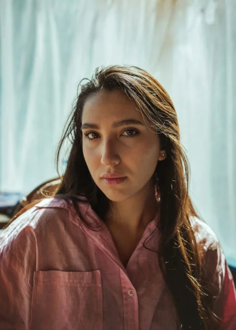 A woman poses, staring directly at the camera