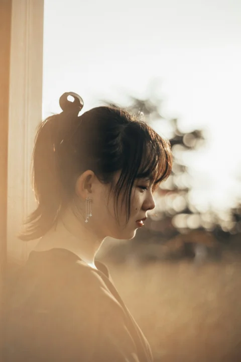 woman in black hair looking at the window