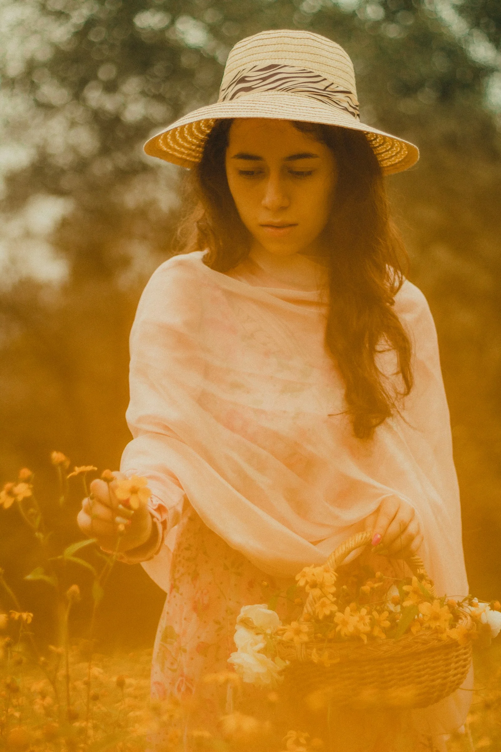 woman in white long sleeve shirt and brown hat standing on yellow flower field during daytime