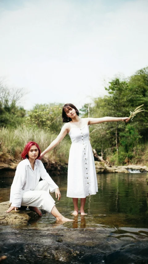 woman in white dress holding her hair standing beside body of water during daytime