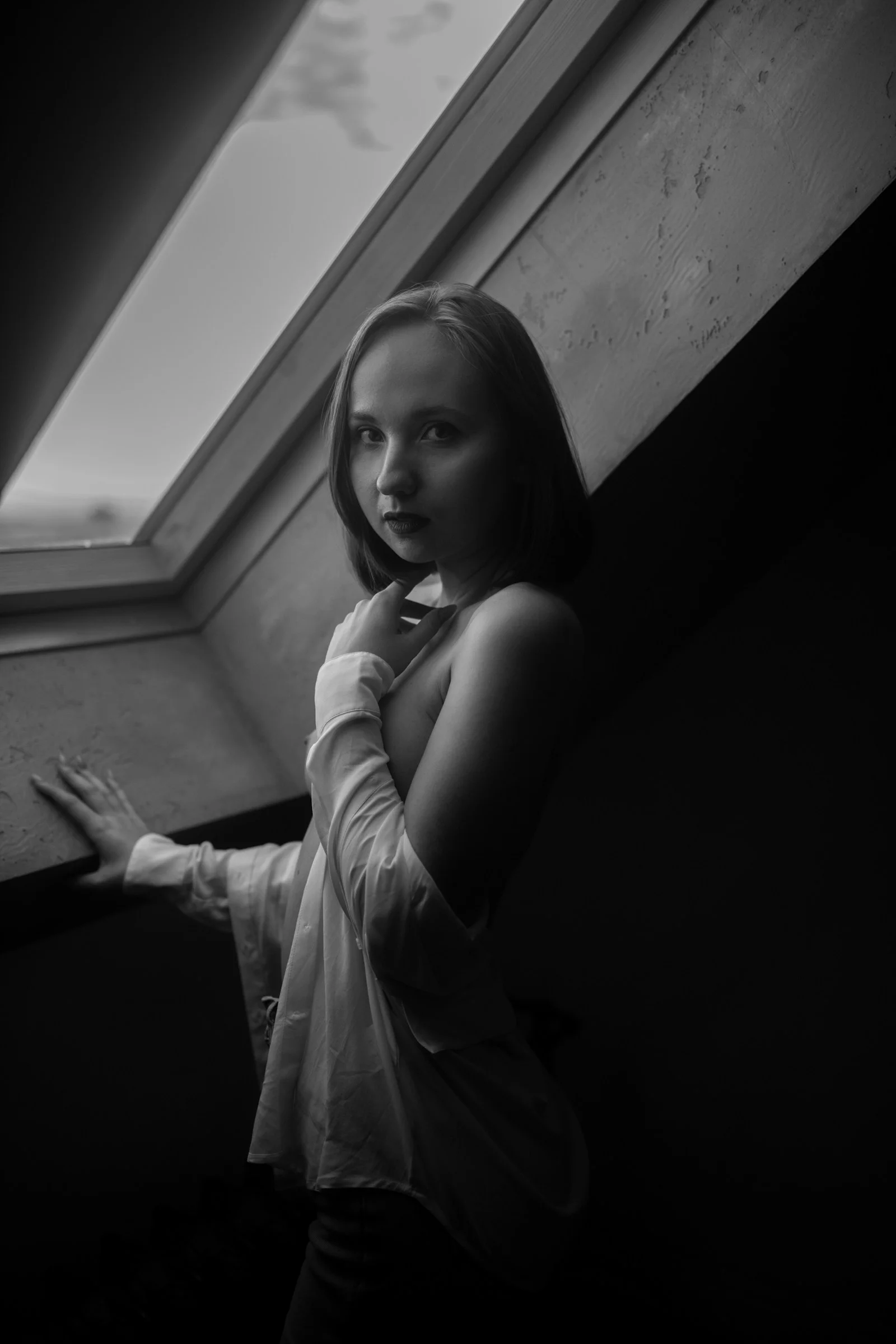 Young woman posing by a window in black and white