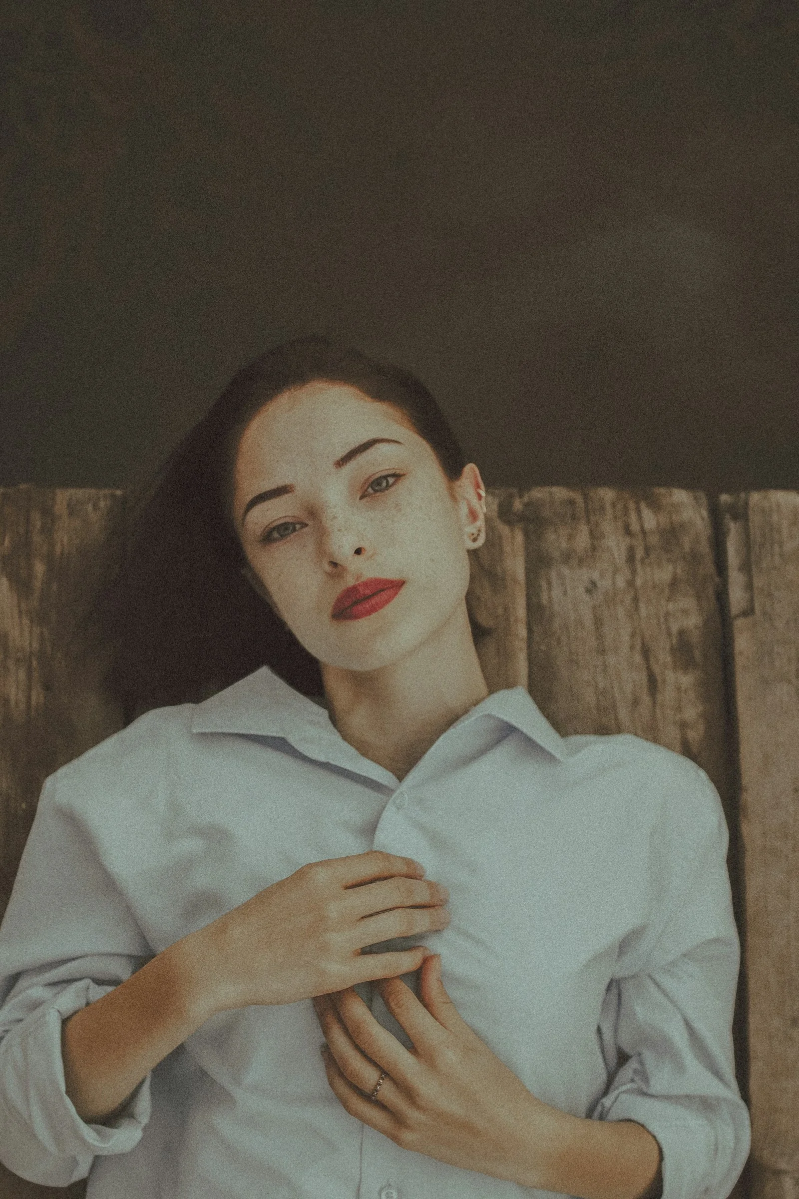 A woman with red lipstick lies on a wooden surface