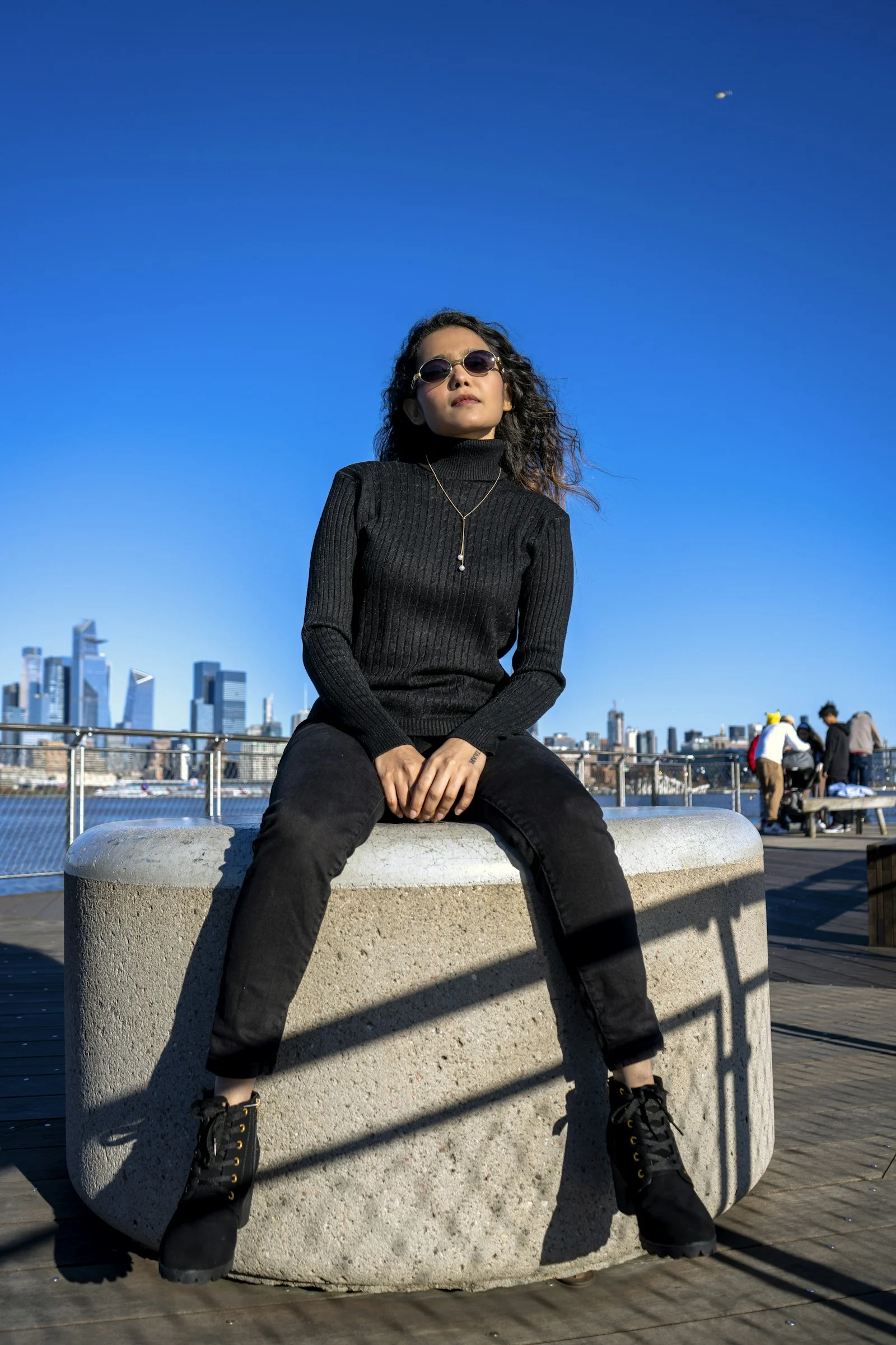 a woman sitting on top of a cement pillar