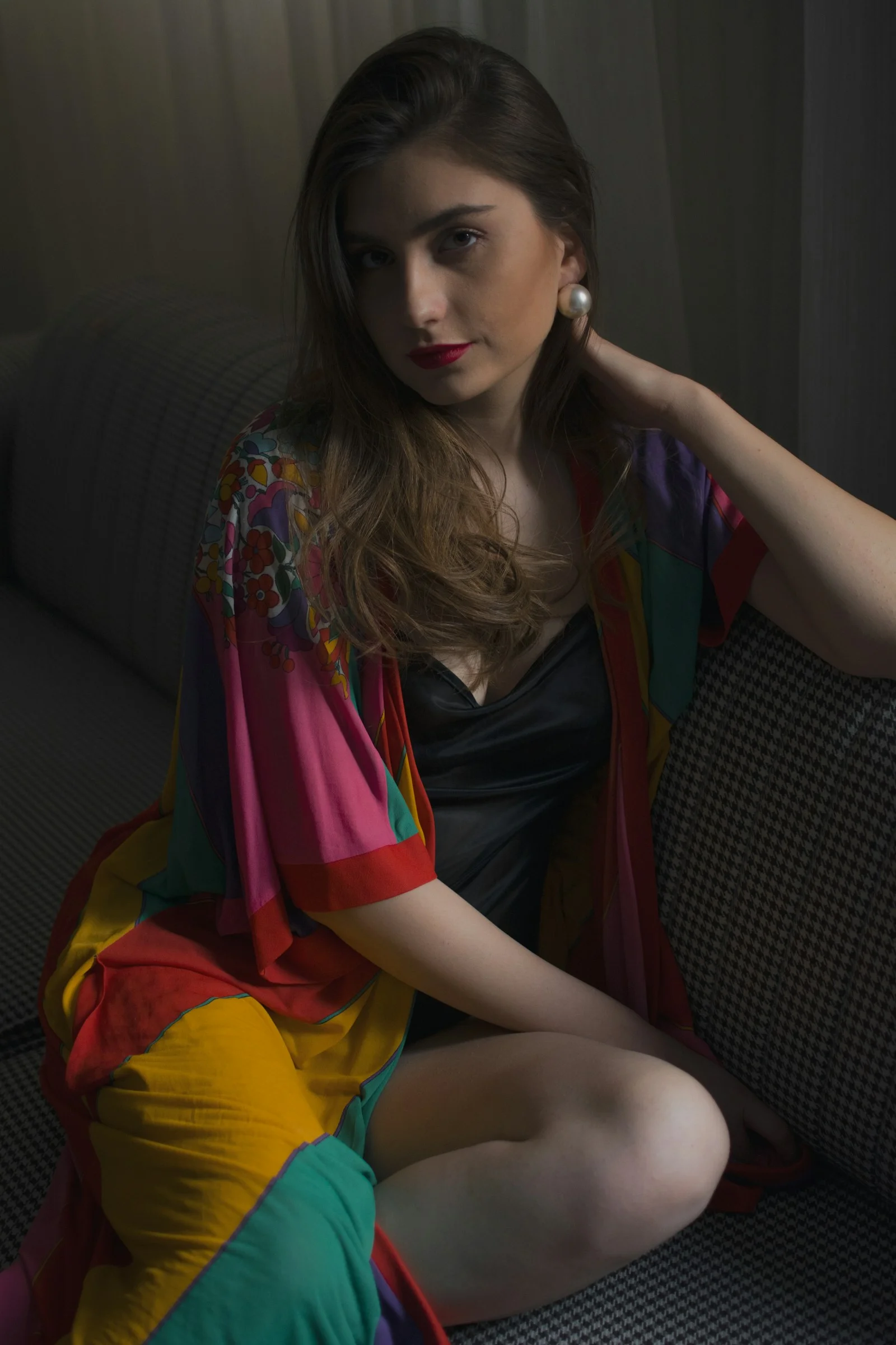 a woman sitting on a couch wearing a colorful dress