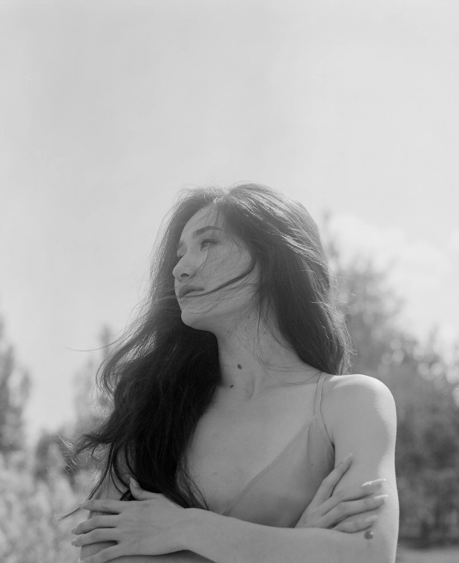 双臂交叉站在田野里的女人
