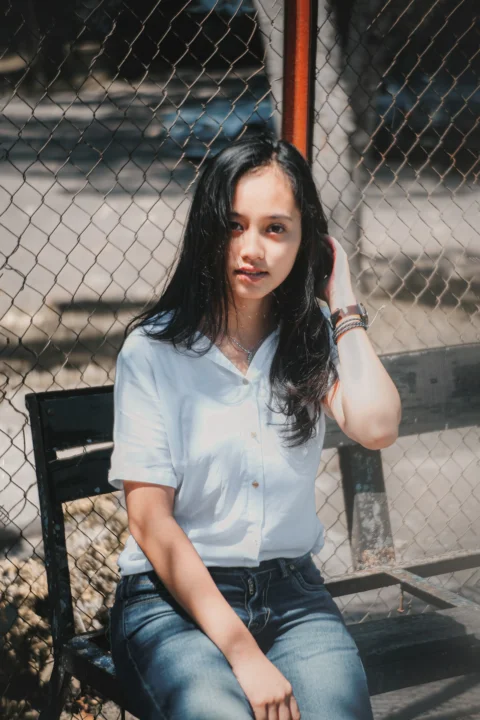 一位女子坐在栅栏前的长凳上