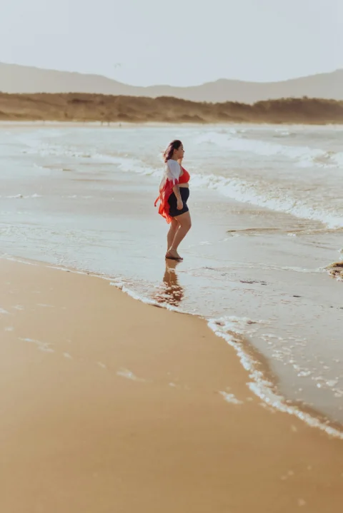 a woman standing on a beach next to the ocean