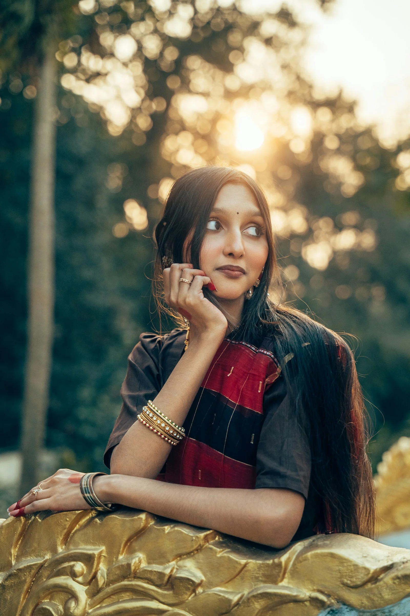 A woman in traditional indian attire poses outdoors at sunset