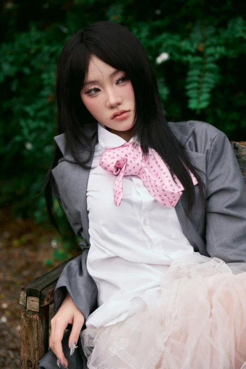 Young woman with dark hair and pink tie sitting outdoors