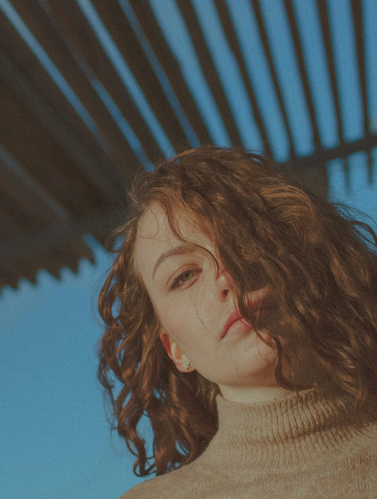 Curly-haired woman in turtleneck under blue sky