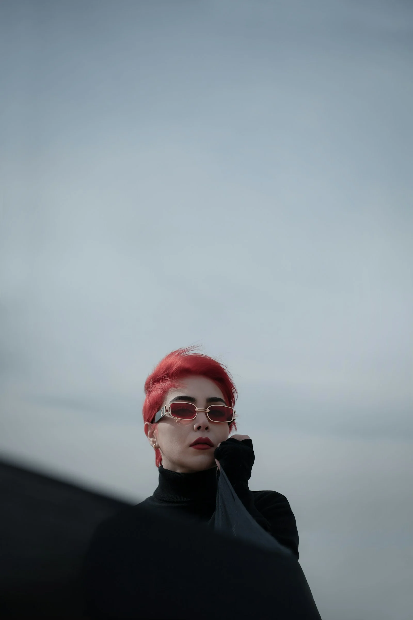 一位紅髮女性戴著太陽眼鏡，身穿黑色上衣