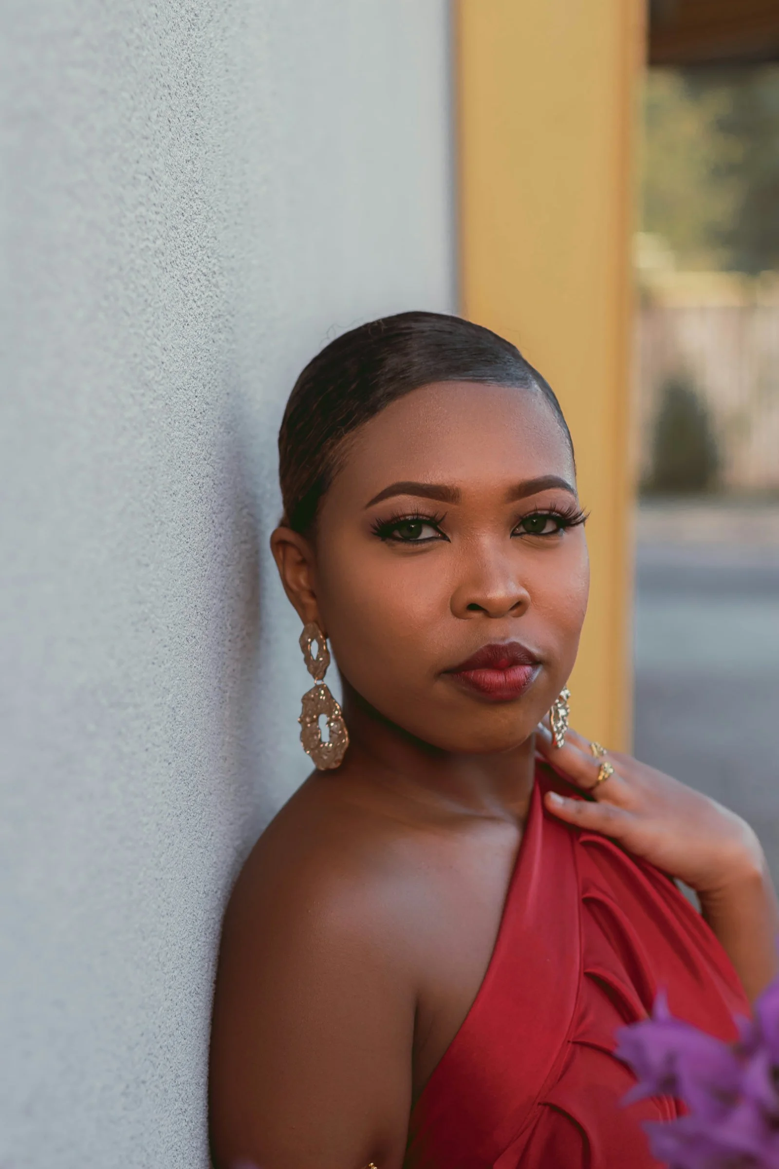 a woman in a red dress leaning against a wall