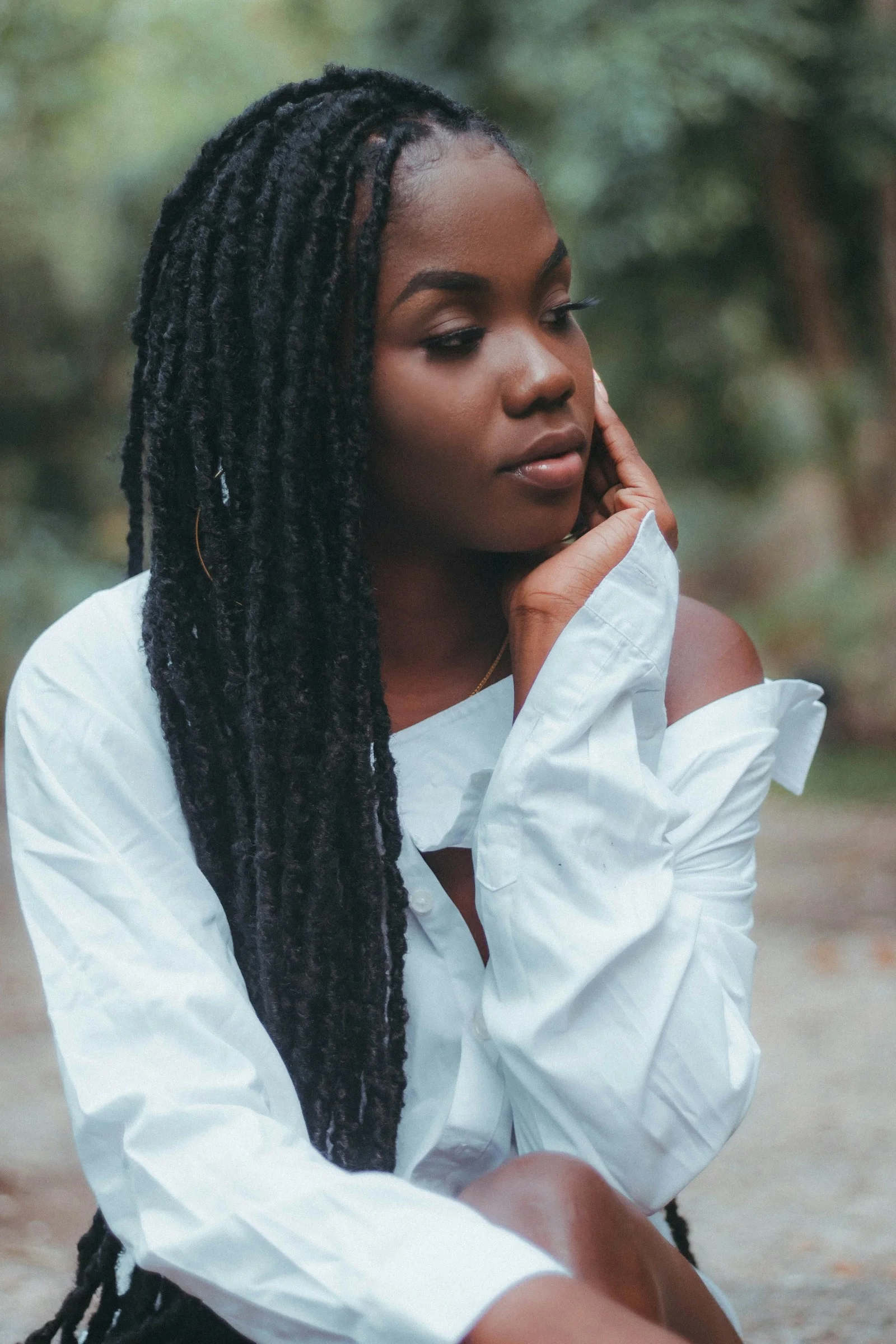 a woman sitting on the ground wearing a white shirt