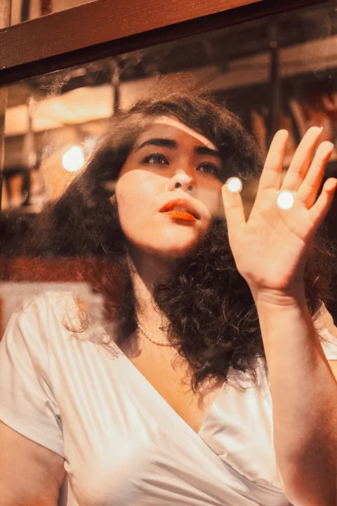 A woman in a white shirt is holding her hand up