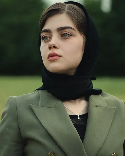 a woman wearing a green jacket and a black scarf