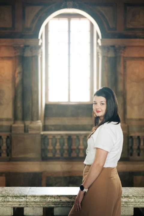 Young woman standing in a grand hall with bright window