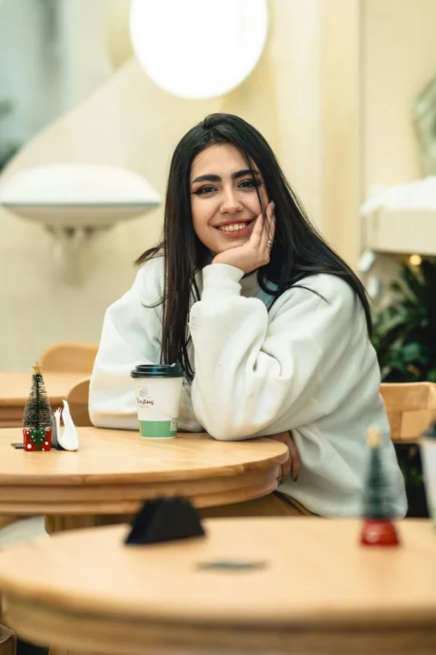 A young woman smiles while sitting at a cafe table