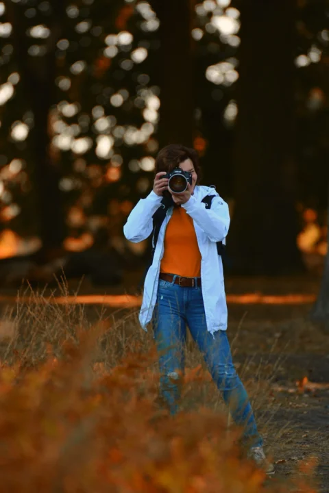 woman in white long sleeve shirt and blue denim jeans holding black dslr camera