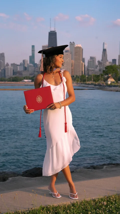 A woman in a graduation gown holding a red book
