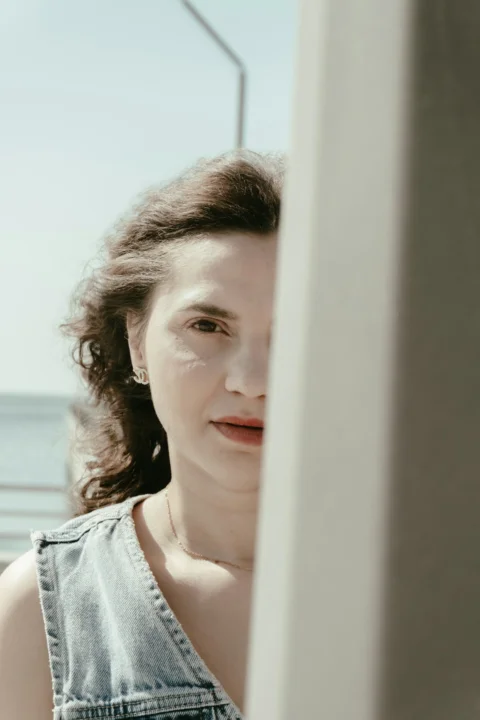 A woman's face partially obscured by a light-colored pillar