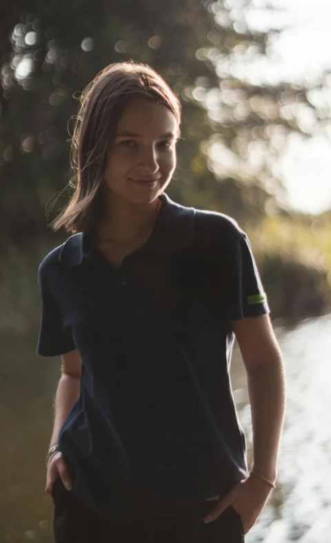 Young person with hands in pockets by water