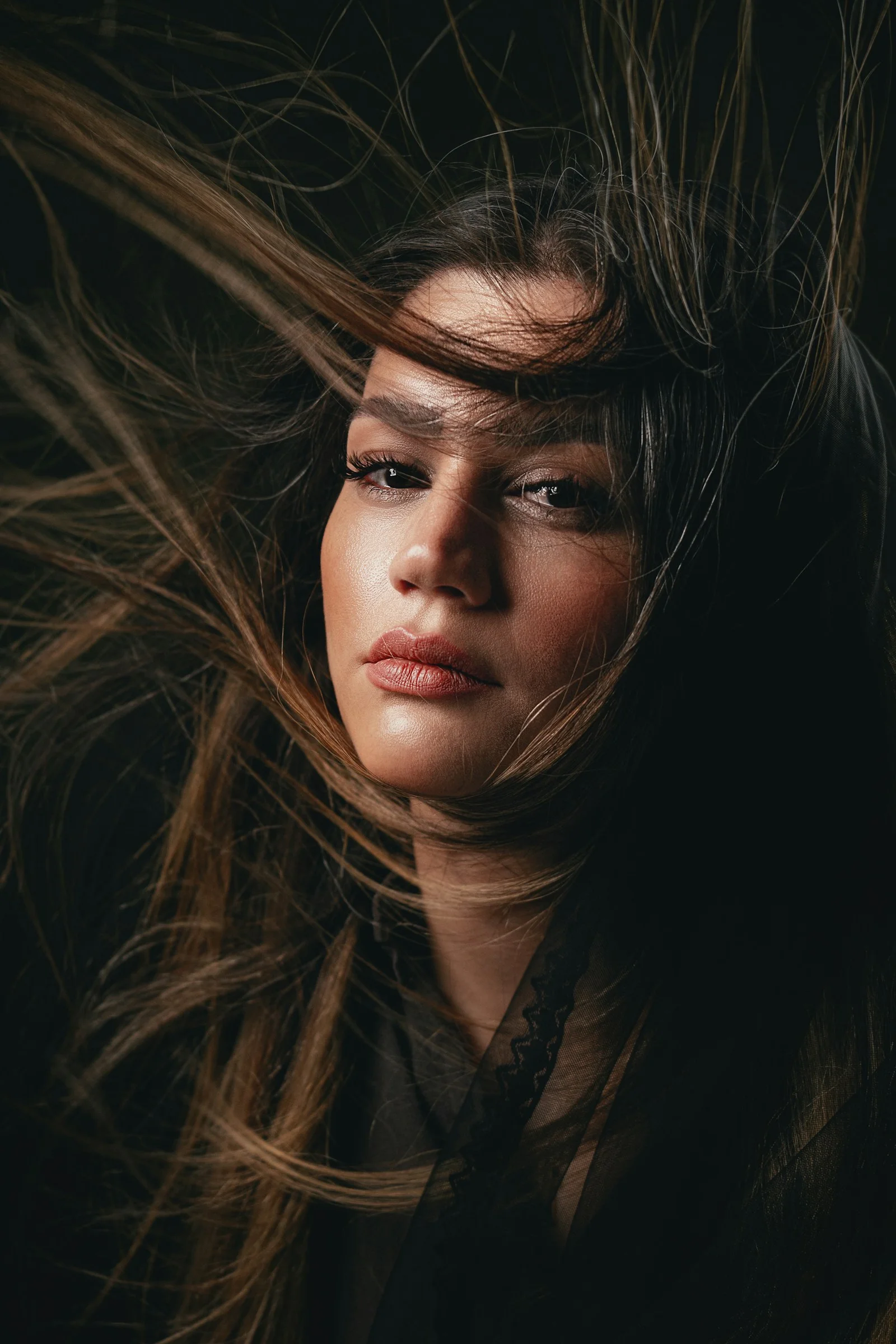 Woman with windblown hair against dark background