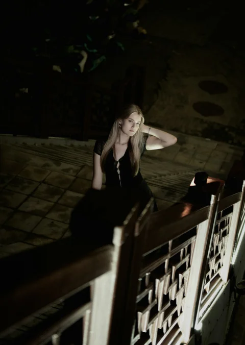 Young blonde woman sits on dark tiled floor
