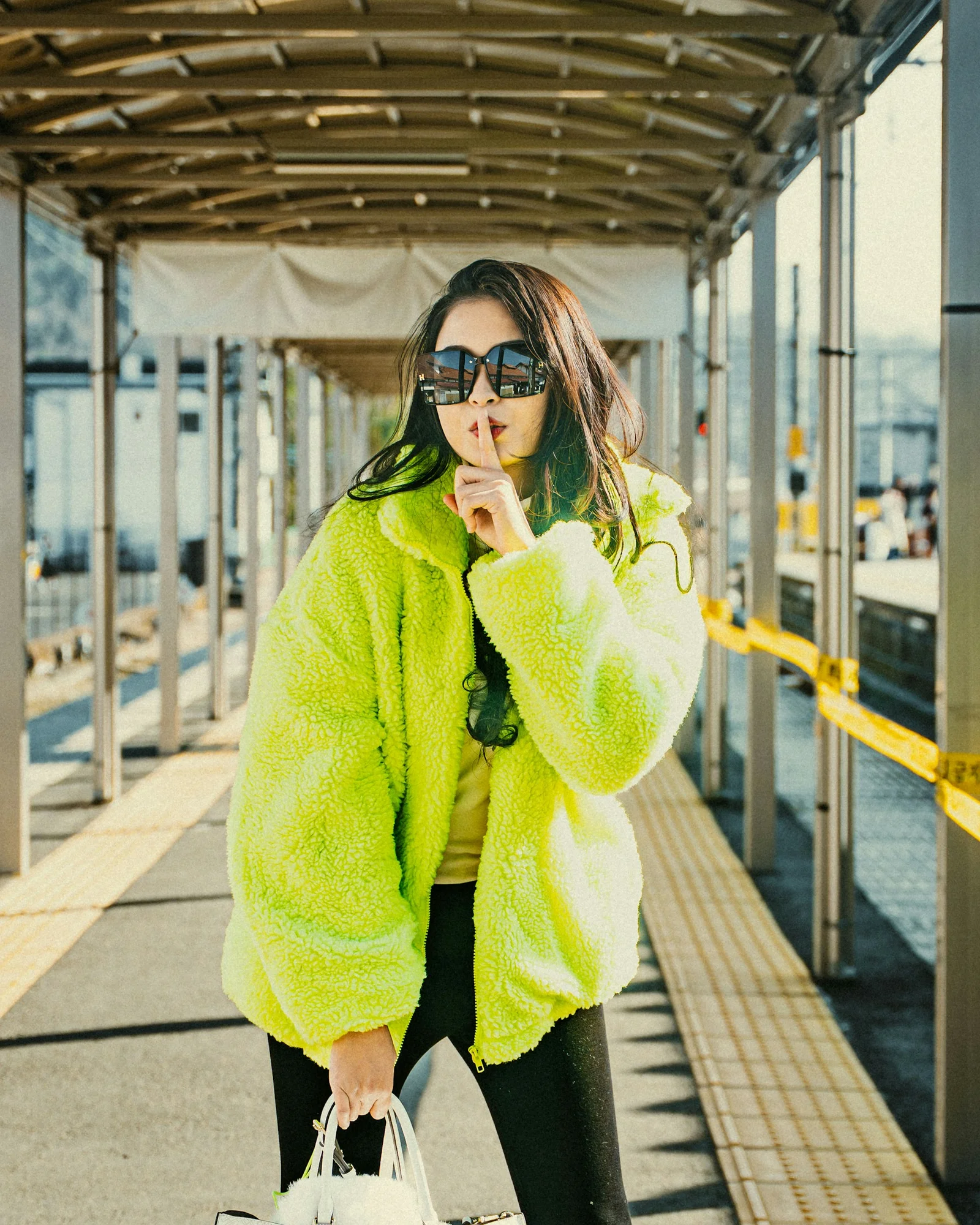 Woman makes a "shhh" gesture while wearing neon green jacket