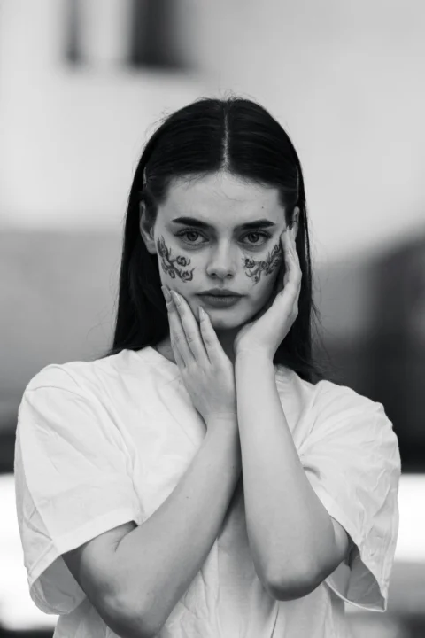 A woman with face paint holding her hands to her face