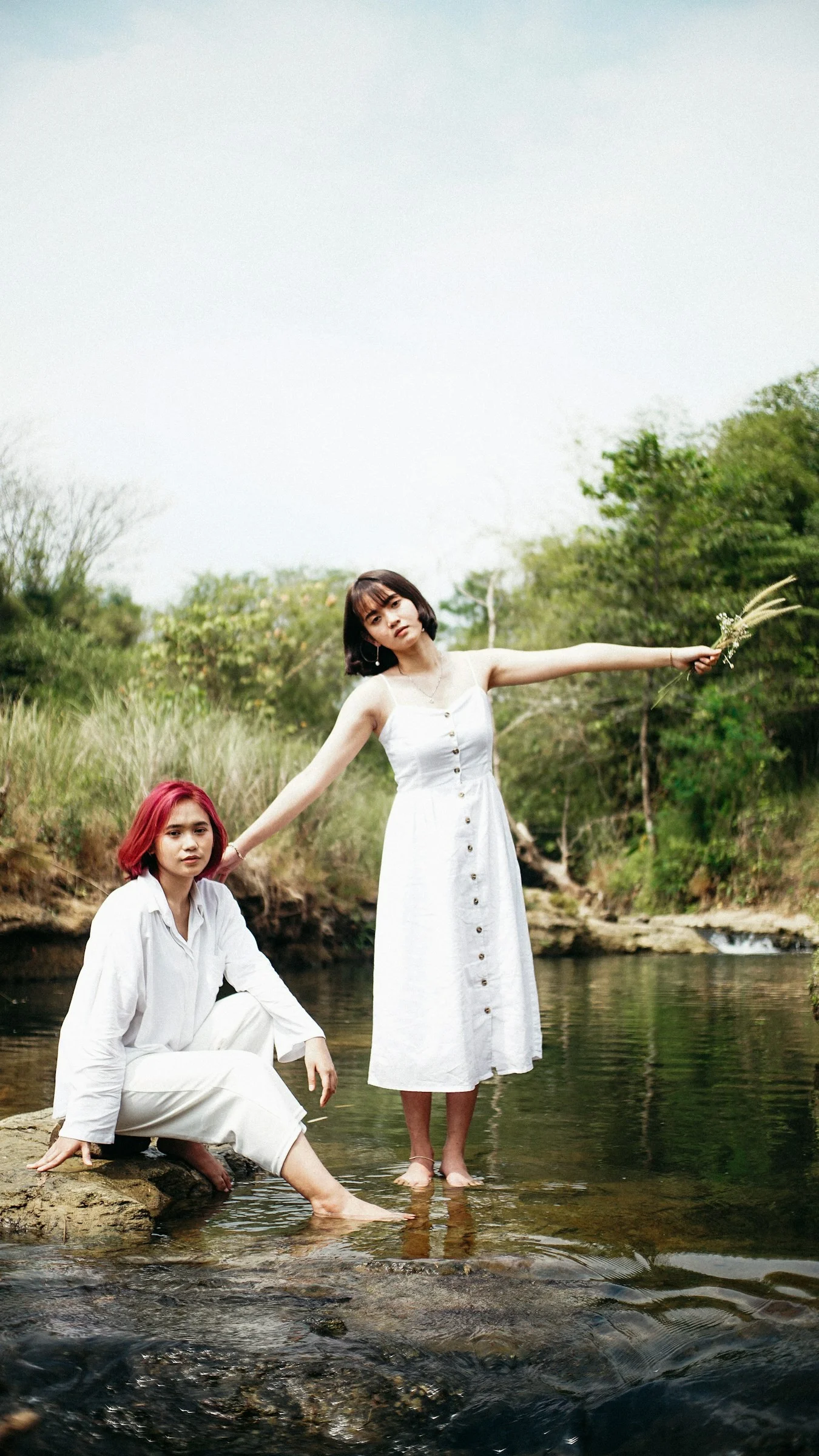 woman in white dress holding her hair standing beside body of water during daytime