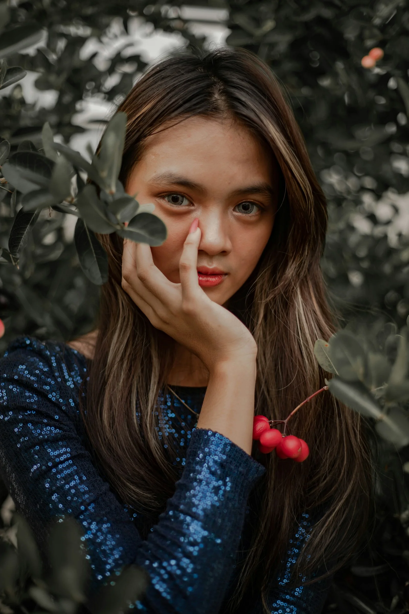 a woman with long hair holding her hand to her face
