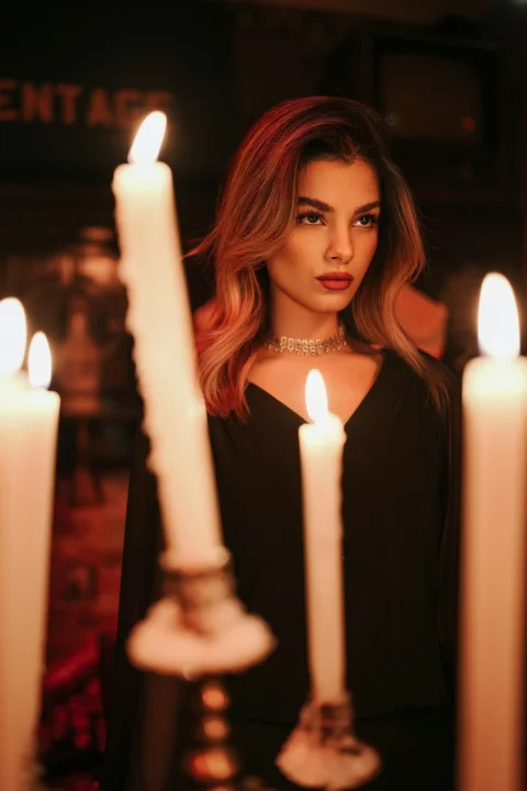 A woman in a black top behind several lit candles in a dark room