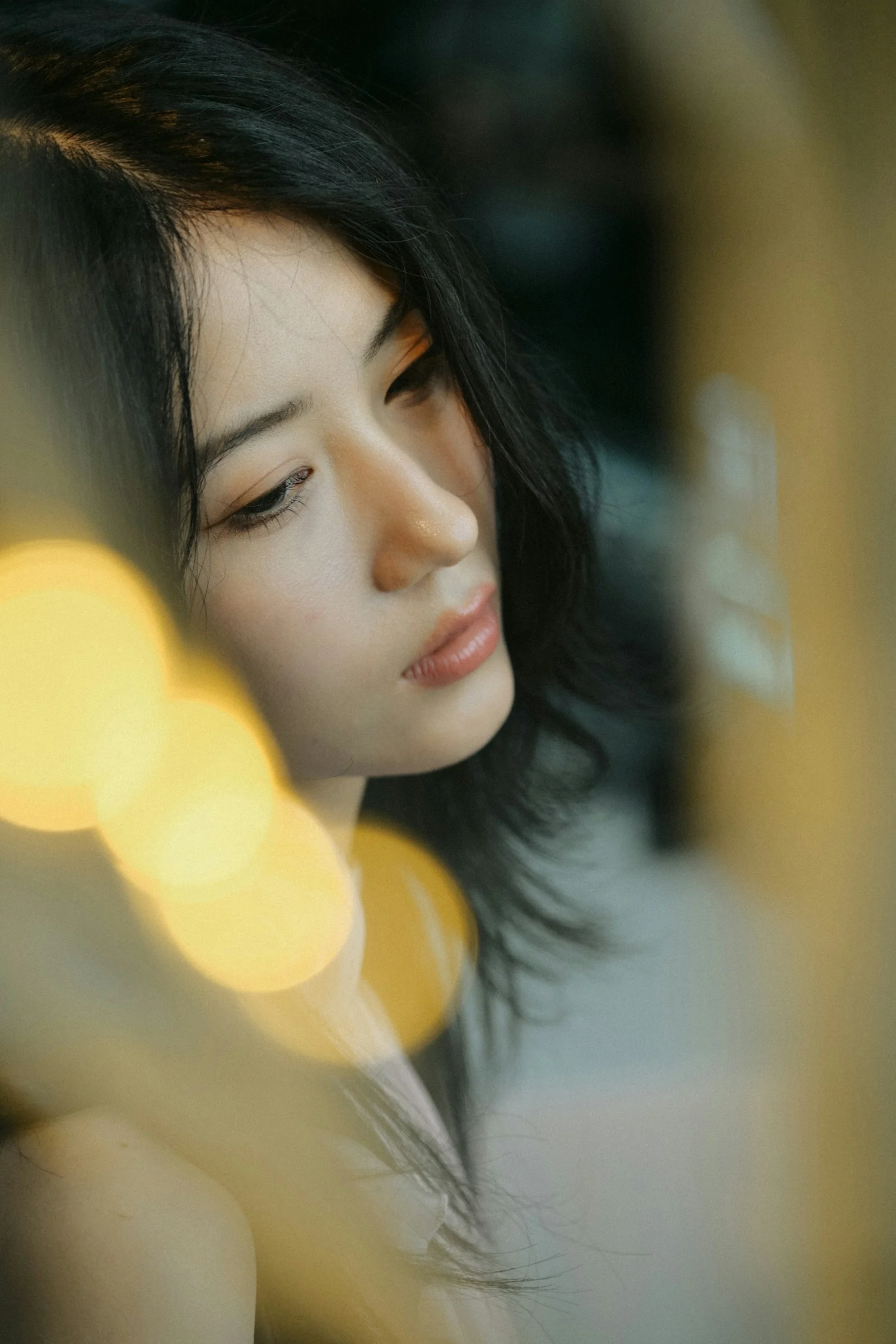 보케에 둘러싸여 다른 곳을 바라보는 검은 머리의 젊은 여성