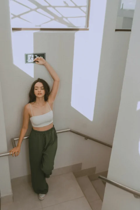 a woman in a white top and green pants