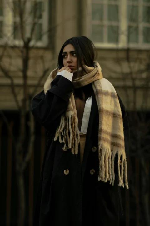 A woman wearing a black coat and a plaid scarf